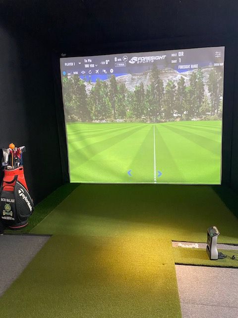 A woman is swinging a golf club in a golf simulator.
