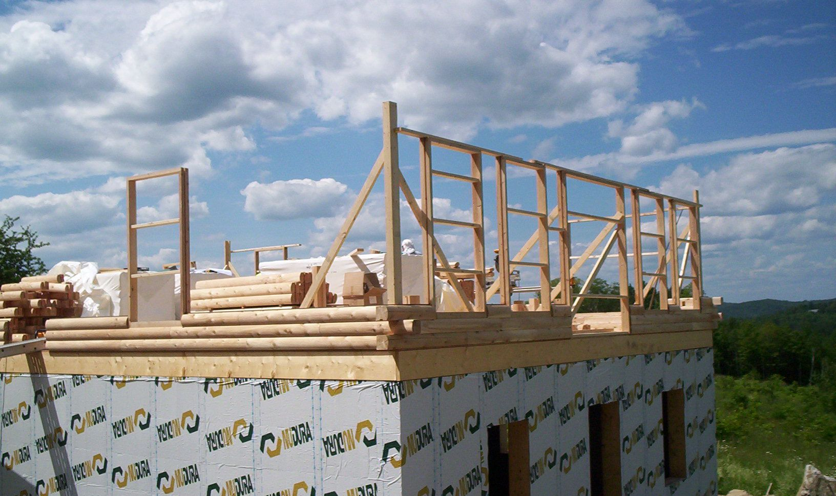 Wood-framed house under construction with plywood walls and blue sky overhead