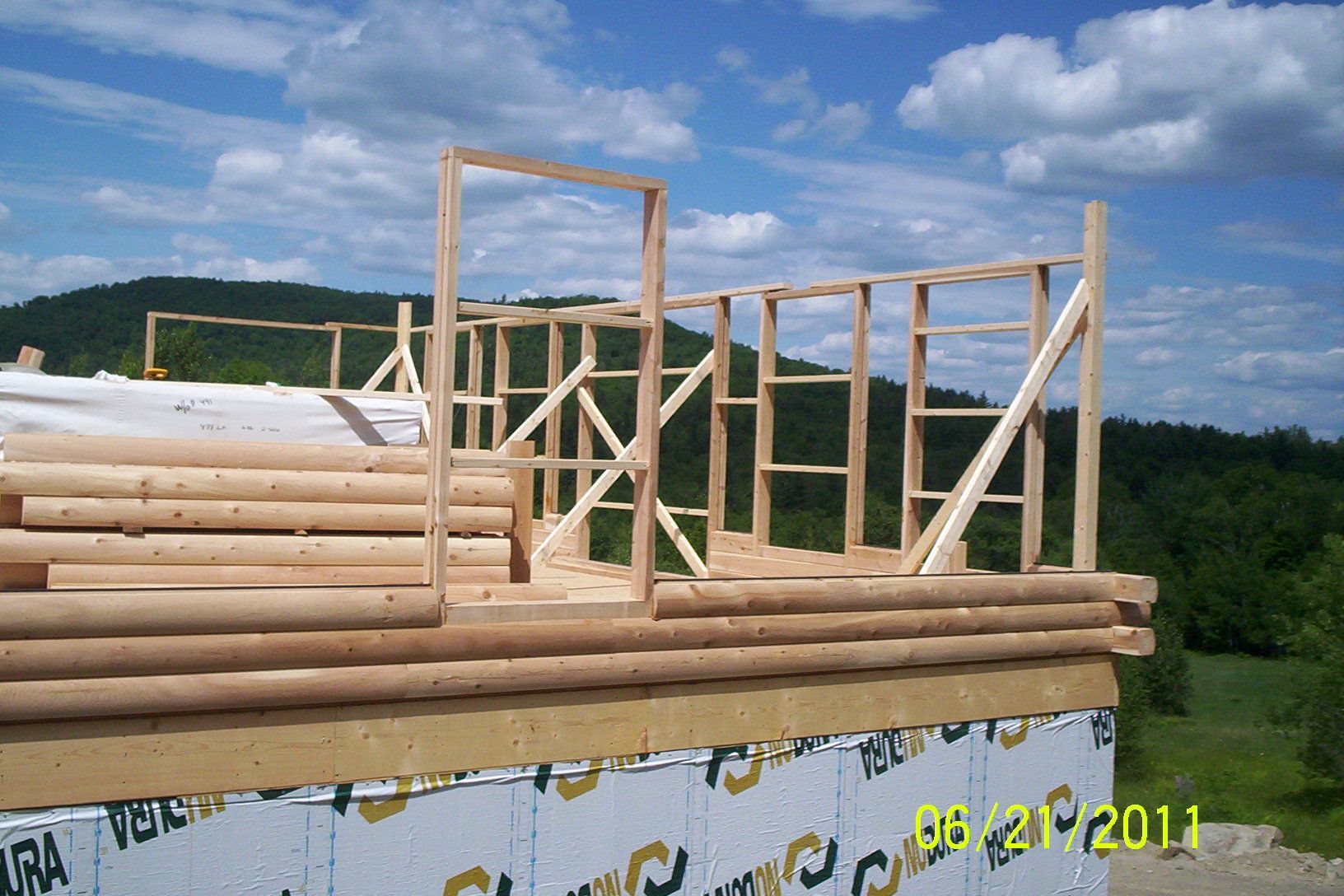 Wooden house frame under construction on a flatbed truck outdoors under a blue sky