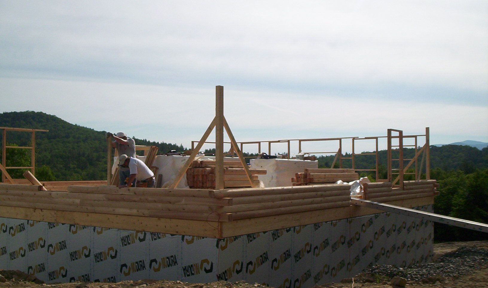 Building frame under construction on a rooftop, with wooden beams and a cloudy sky in the background