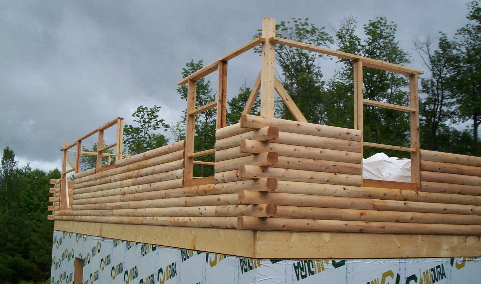 Partially built log cabin walls with wooden frame under construction on a foundation outdoors