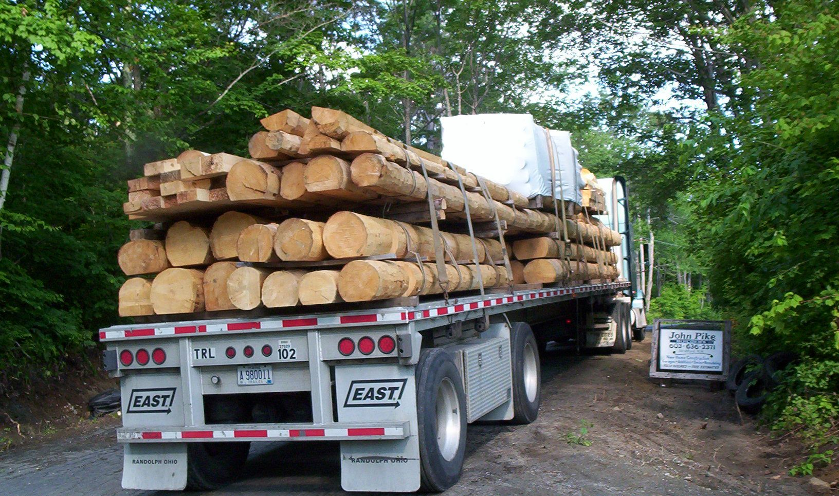 Logging truck loaded with stacked logs on a forested dirt road