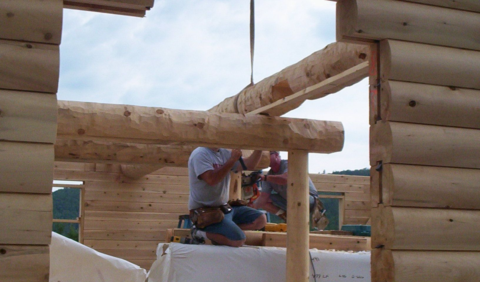 Worker assembling wooden beams in a log cabin frame under construction