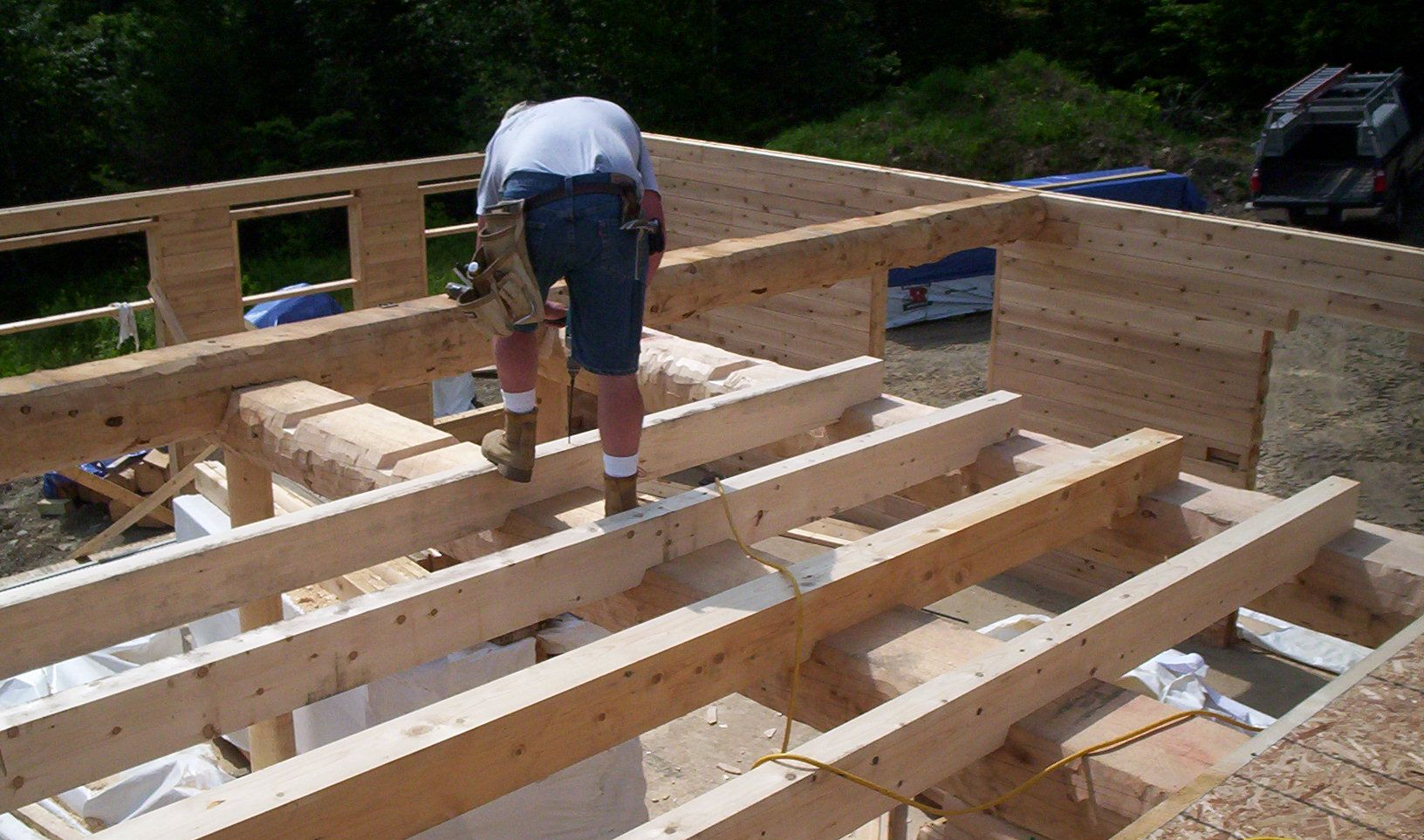 Person working on wooden floor framing at a construction site