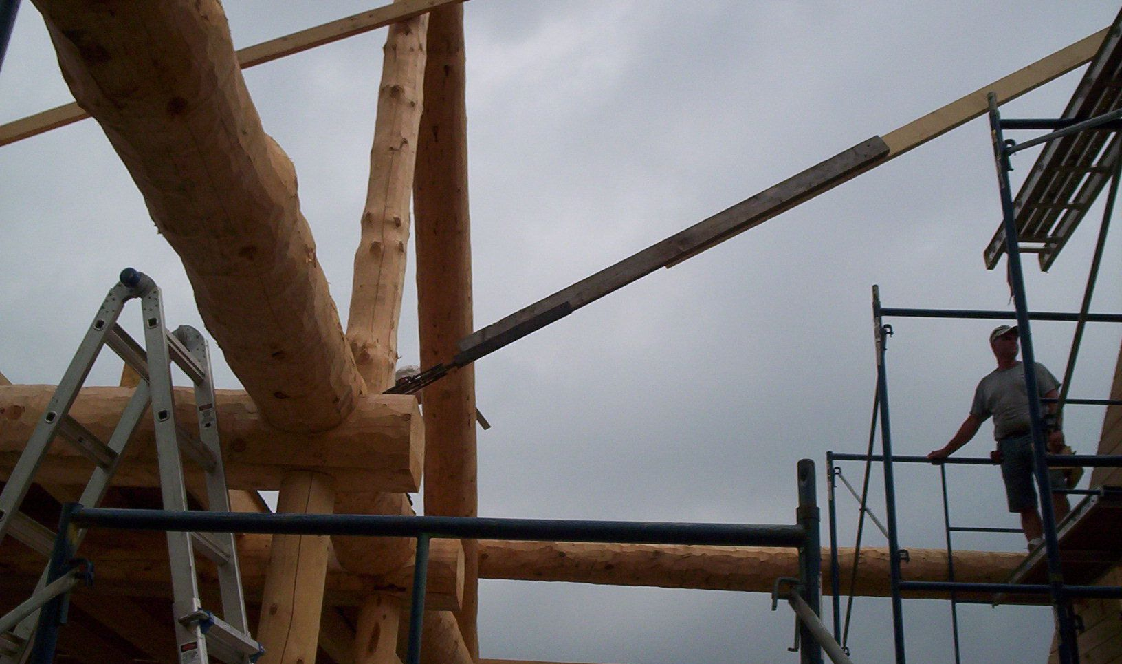 Workers on scaffolding beside a large wooden structure under construction.