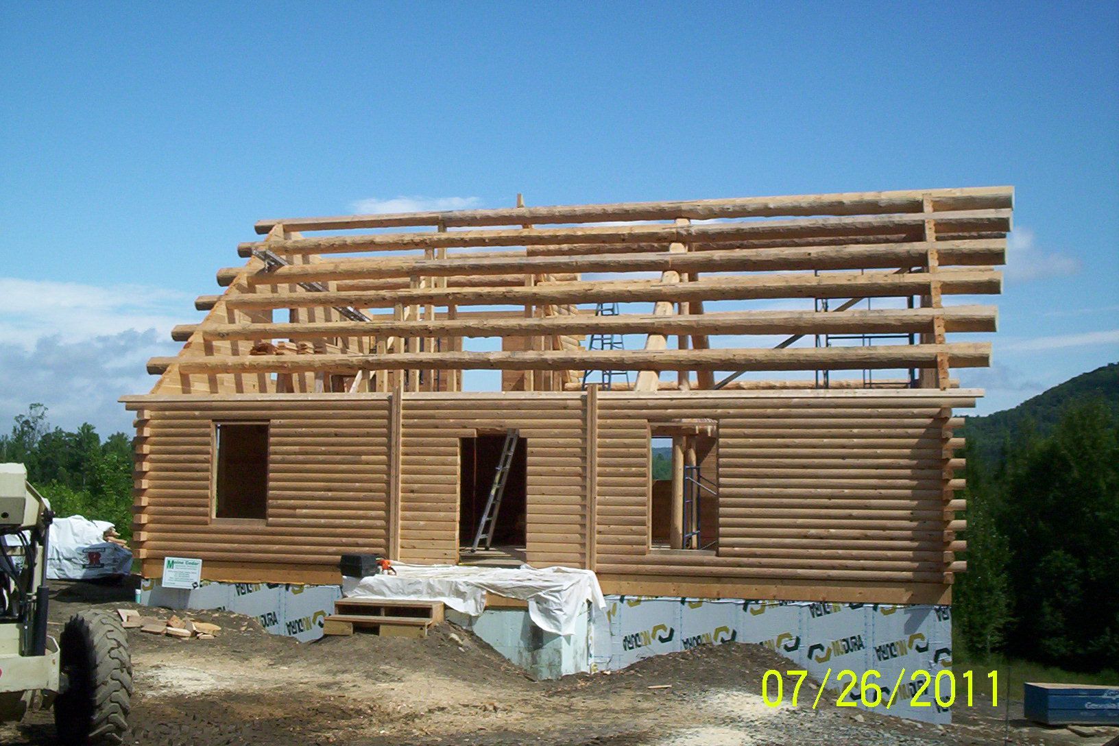 Partially framed wooden house under construction with a blue sky background