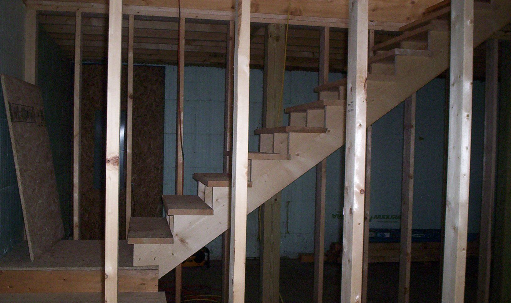 Exposed wooden staircase and wall studs in an unfinished basement interior