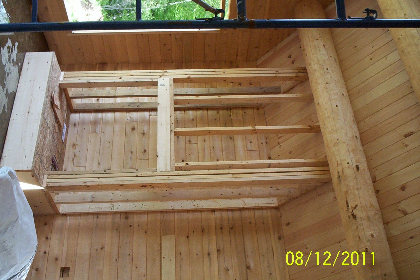 Wooden construction framing for a stair opening inside a house, with plywood walls and floor.