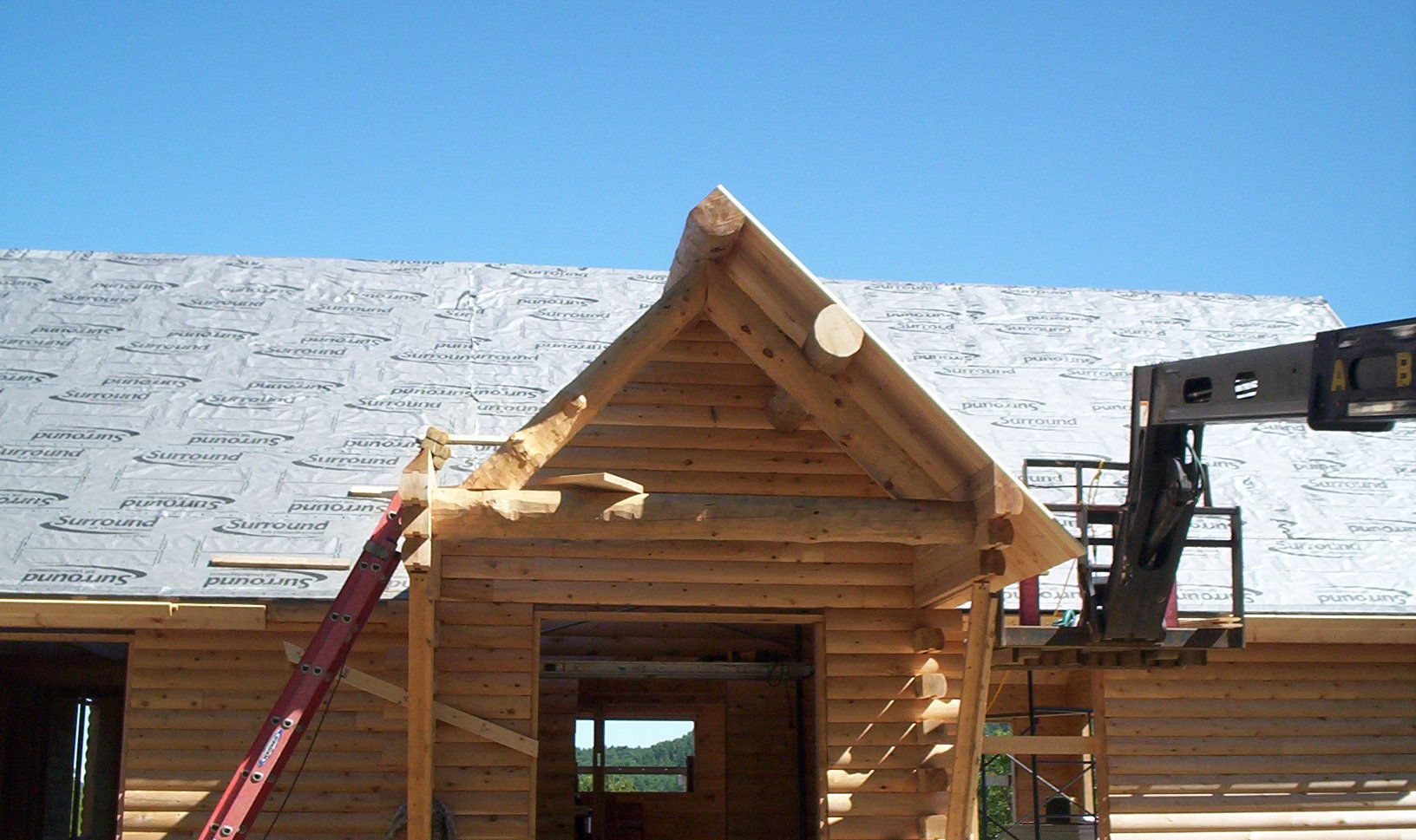 Small wooden cabin frame with a steep roof under construction against a blue sky.