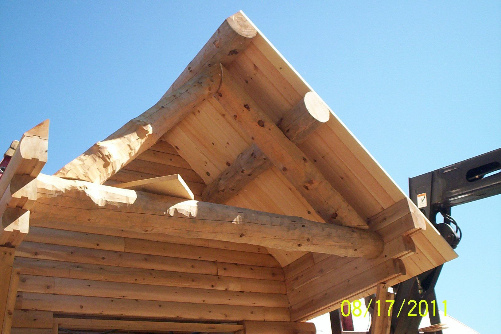 Wooden cabin roof under construction against a blue sky