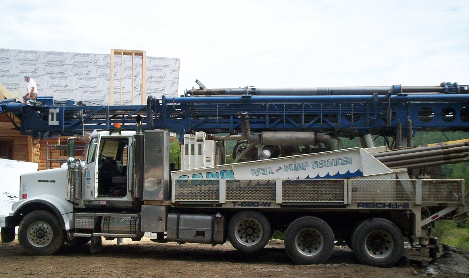 White dump truck loaded with gravel parked in front of an industrial conveyor structure