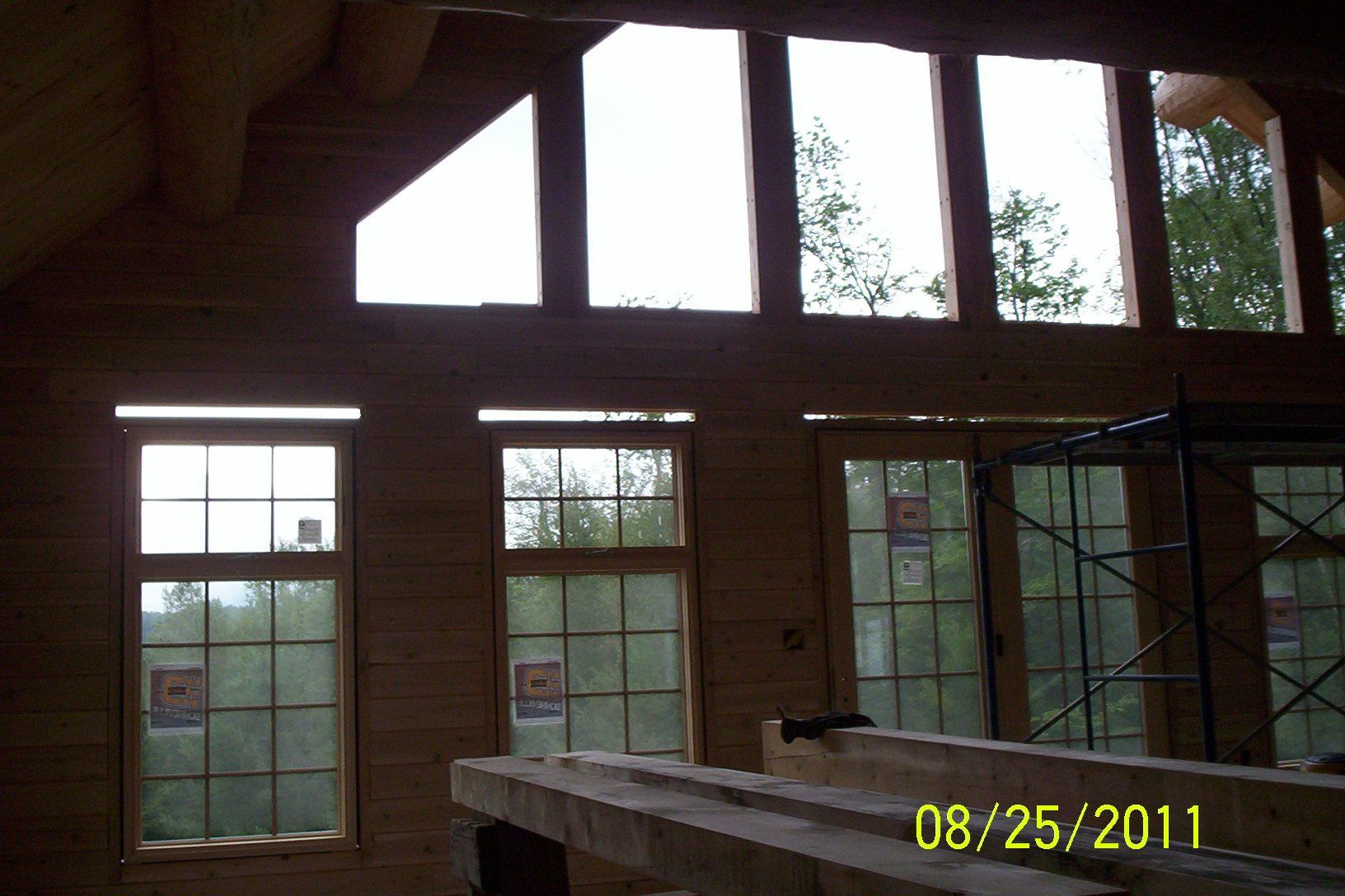 Wood-paneled interior with large windows and a loft railing, lit by daylight