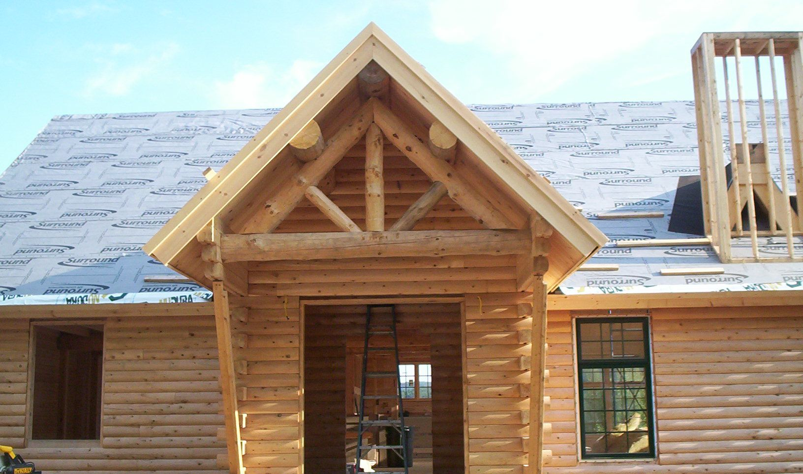 Wooden house under construction with a gabled entry and exposed roof framing