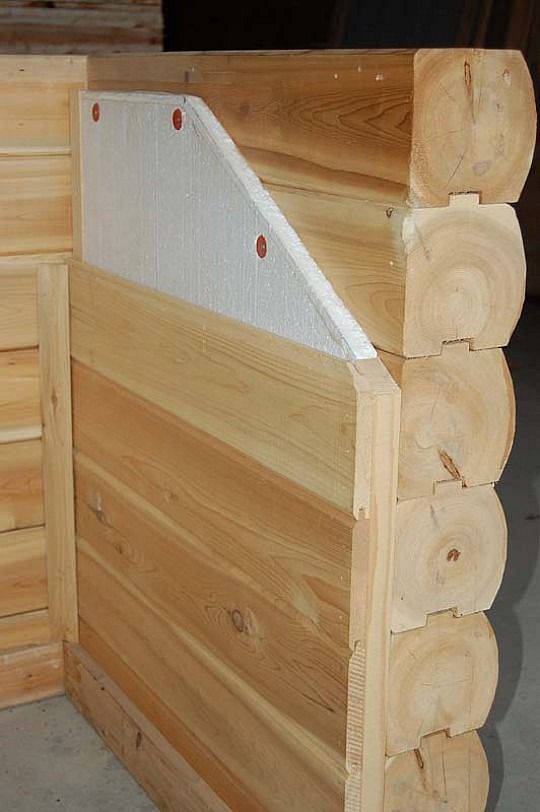 Wooden log cabin wall with a diagonal white panel and visible log ends on the right