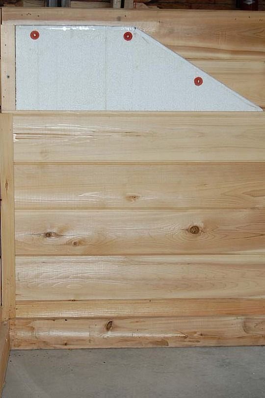 Wooden wall with a white angled panel marked by three red dots near the top.