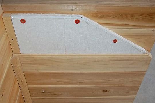 Wooden wall panel with a white triangular insert and three red fasteners.