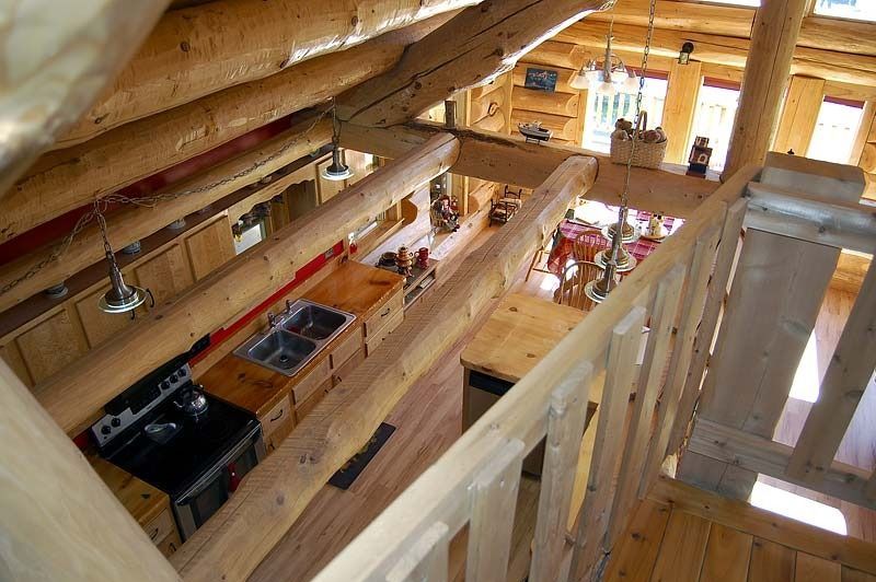 Interior of a timber house under construction with exposed beams and unfinished wooden framing.