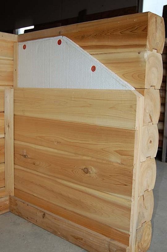 Wooden box corner with horizontal planks and a white triangular panel, secured by red screws