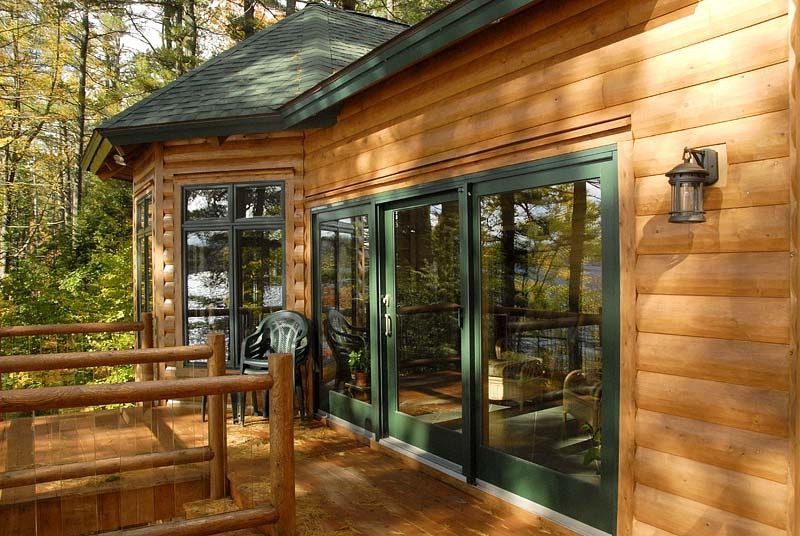 Wooden cabin deck with sliding glass doors and forest views in warm sunlight