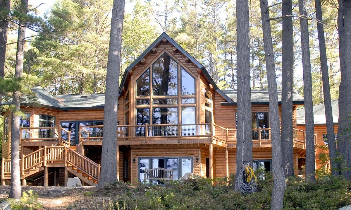 Wooden cabin with large windows among tall pine trees in a forest clearing