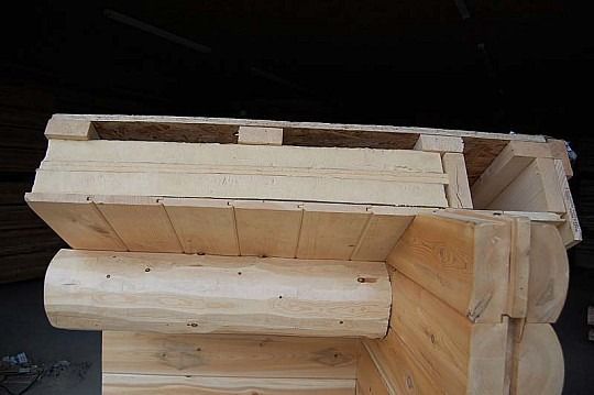 Close-up of a wooden log cabin corner with interlocking logs and roof beams