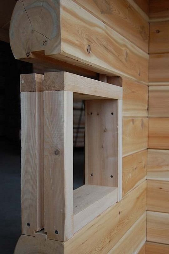 Wooden framed window opening in a log cabin wall, viewed from inside.