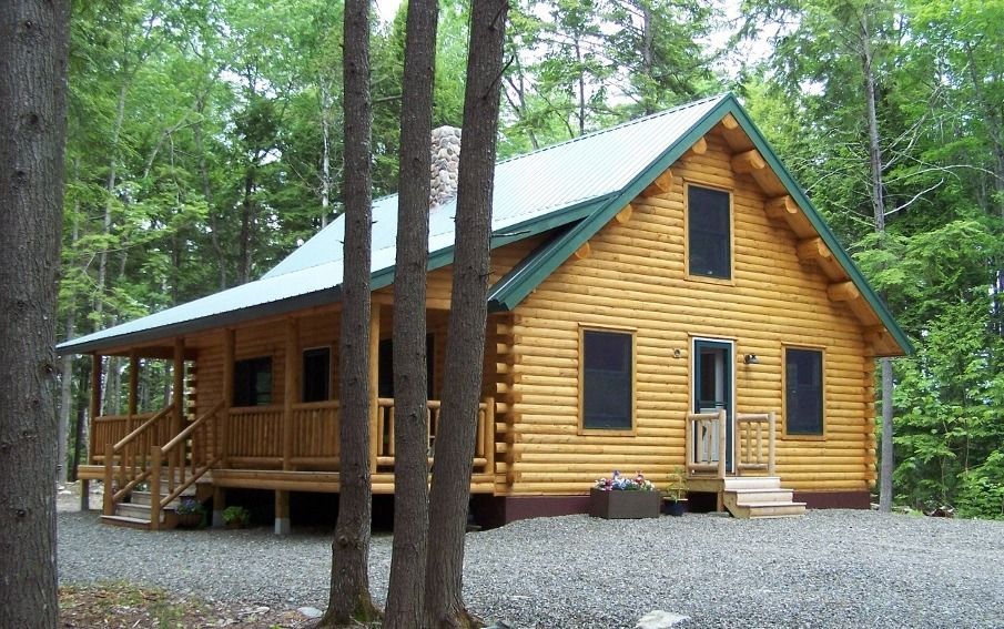 Yellow wooden cabin with green roof in a wooded area