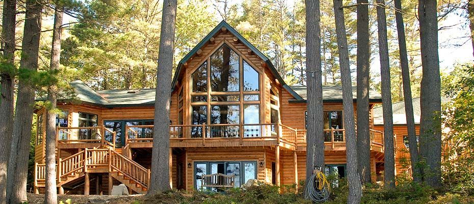 Wooden A-frame cabin with large windows in a pine forest