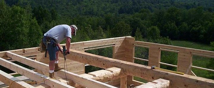 Worker framing a wooden house foundation on a sunny hillside