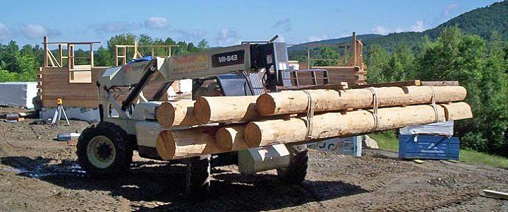 Logging machine carrying stacked cut logs in a rural work yard
