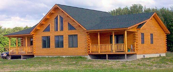 Log cabin-style wooden house with a porch and large windows in a grassy yard