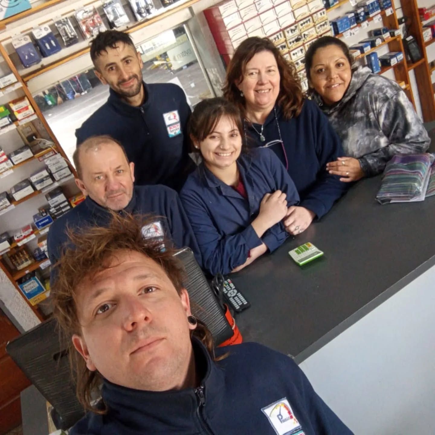 Tres personas conversan sobre aparatos electrónicos en el mostrador de una tienda de electrónica.