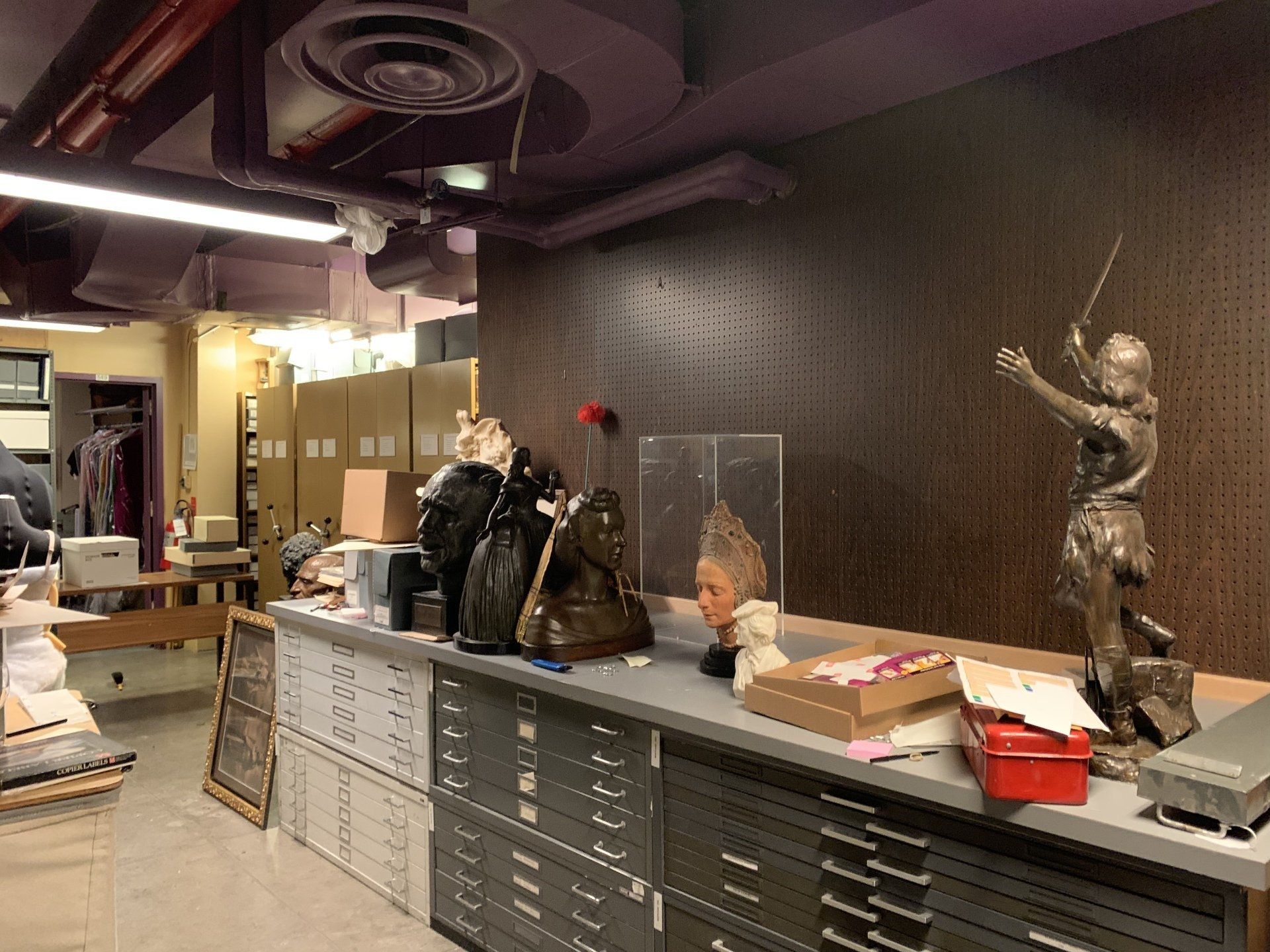 Storage room with artifacts on a workbench, including a statue and boxes.