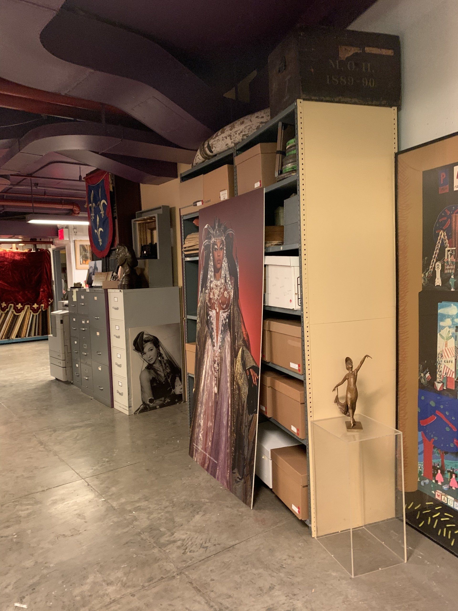 Storage room with shelves, boxes, artwork, and a sculpture.