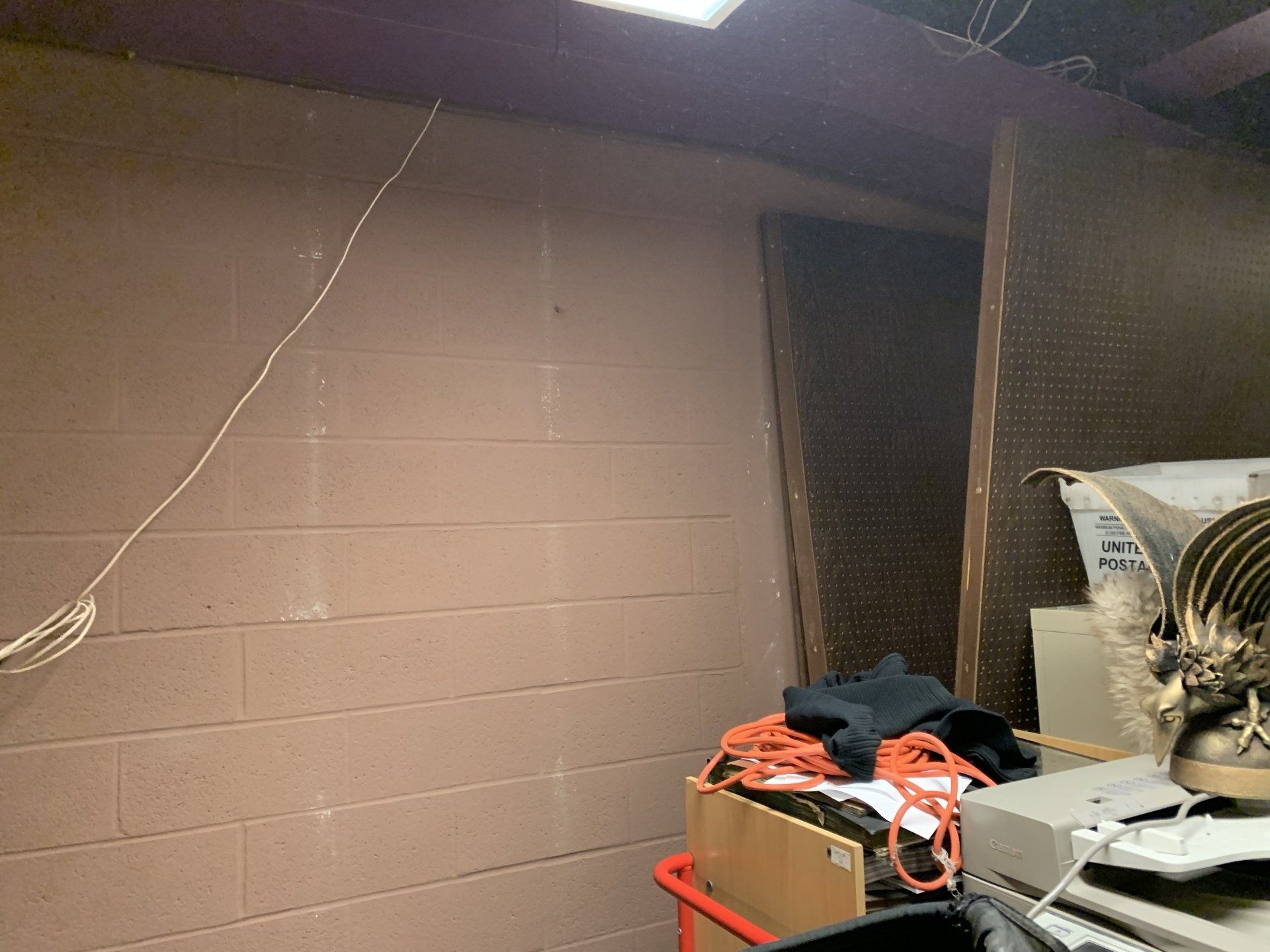 Basement interior with brown brick wall, storage boxes, electrical wiring, and a pegboard.