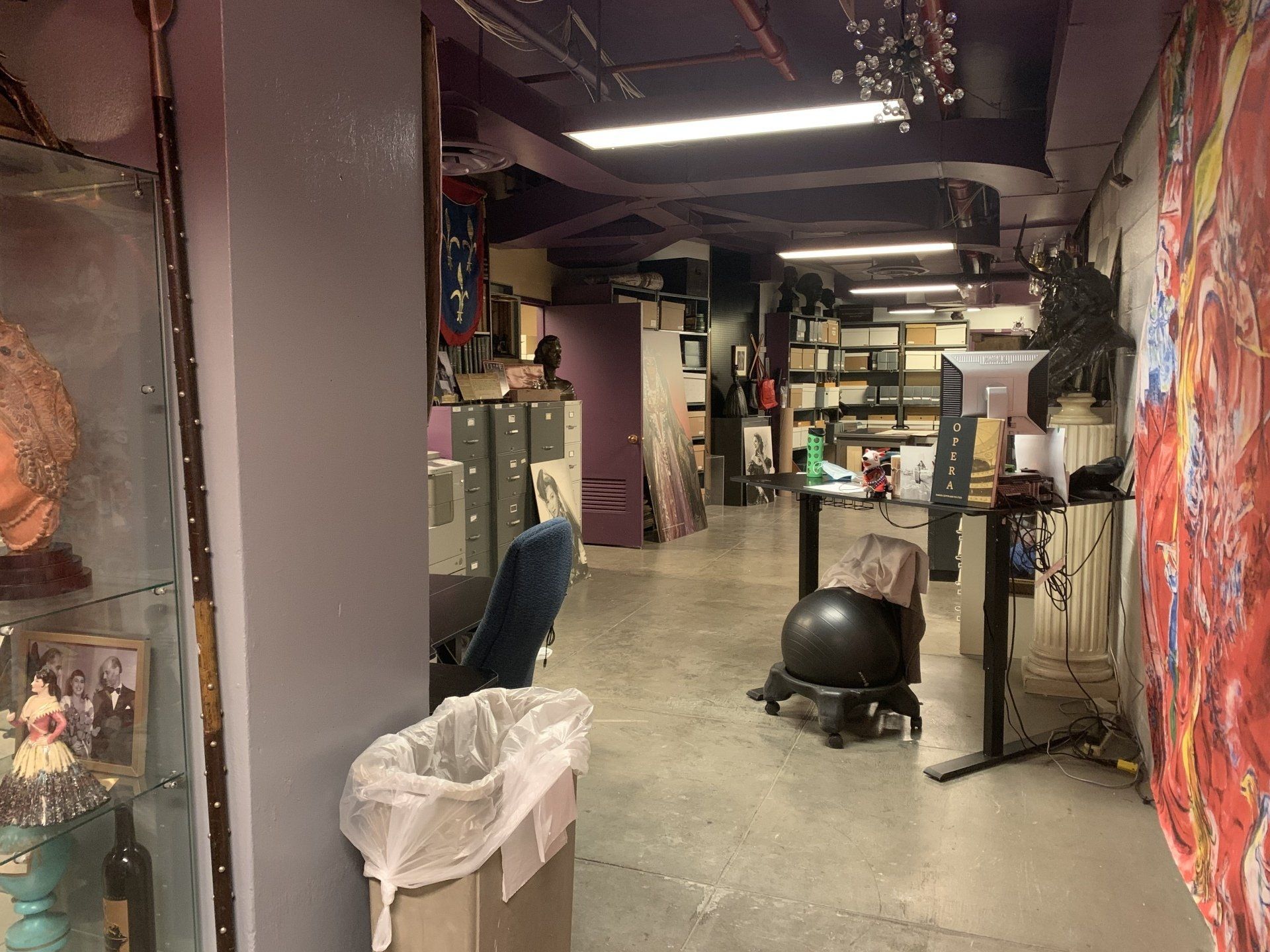 An indoor art studio with a table, chair, shelves, and artwork.