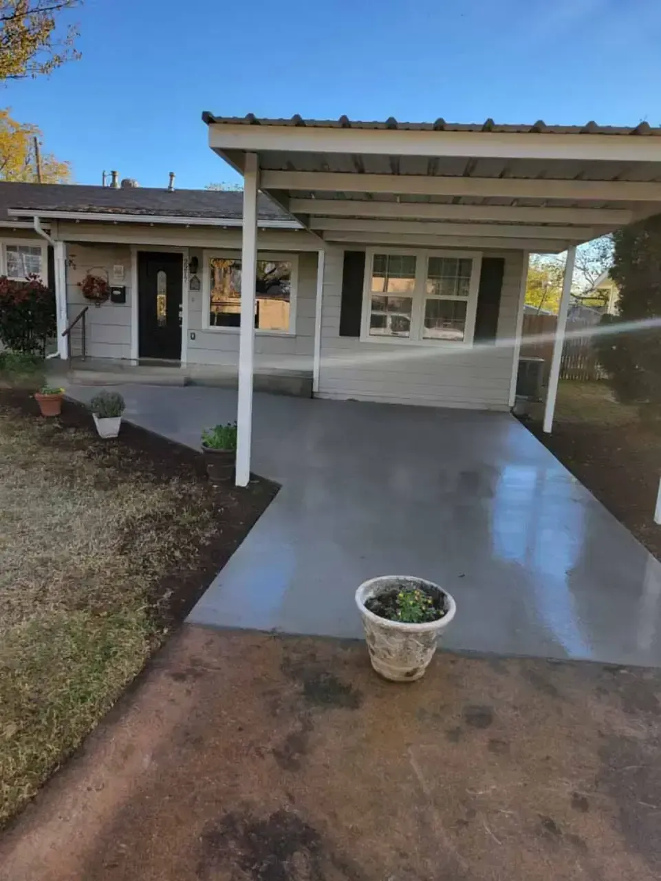 A house with a covered porch and a potted plant in front of it.