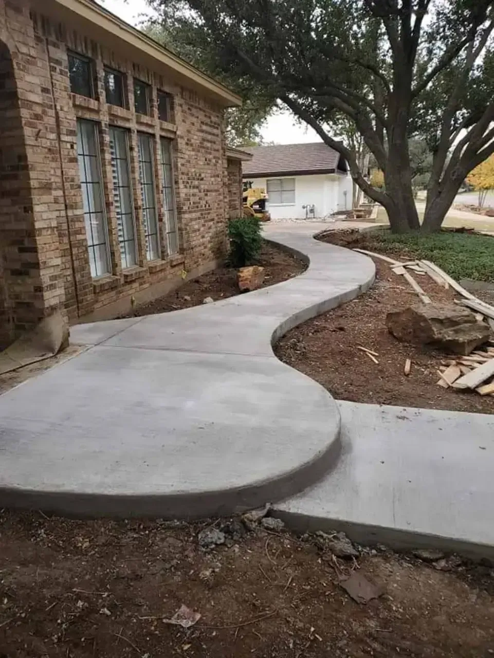 A concrete walkway is being built in front of a brick house.