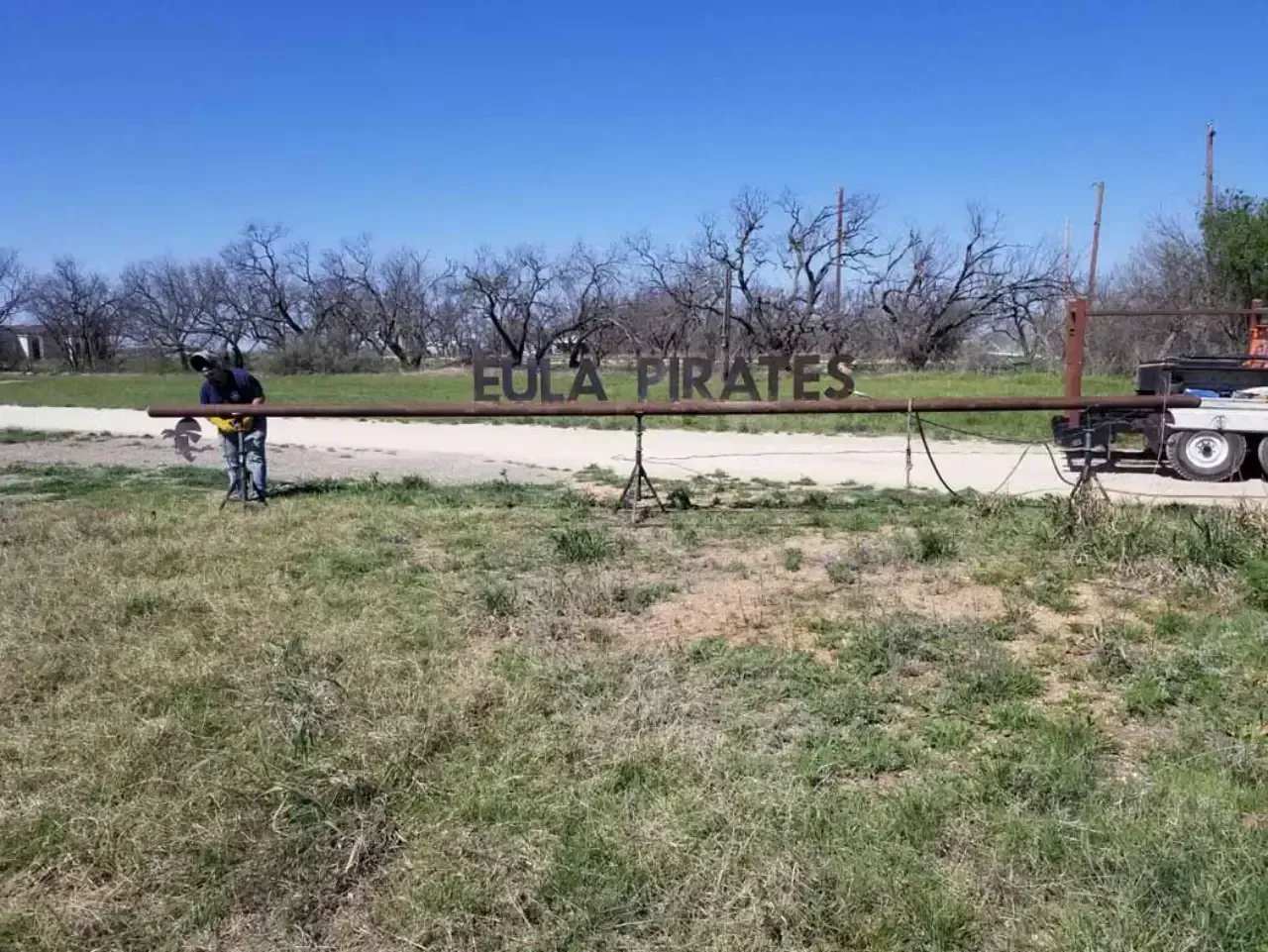 A man is standing in a field next to a sign that says eola pirates.