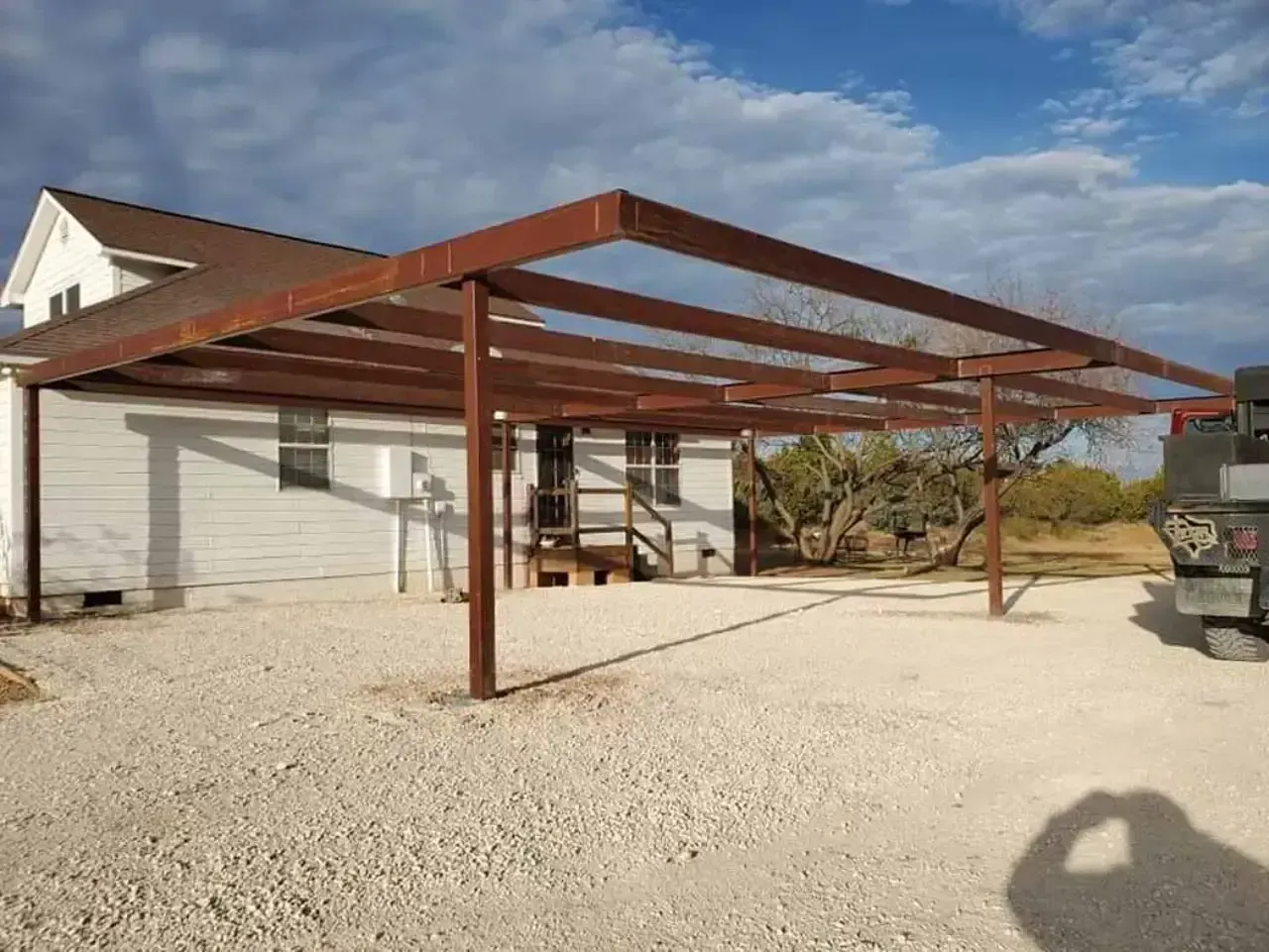 A carport is being built in front of a house.