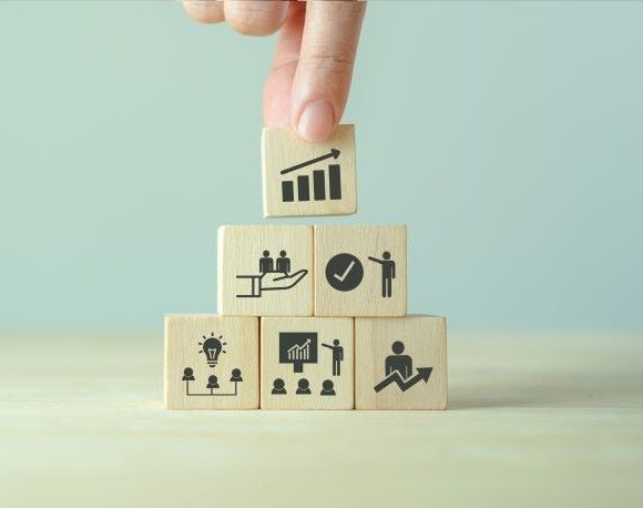 A person is stacking wooden blocks with icons on them.