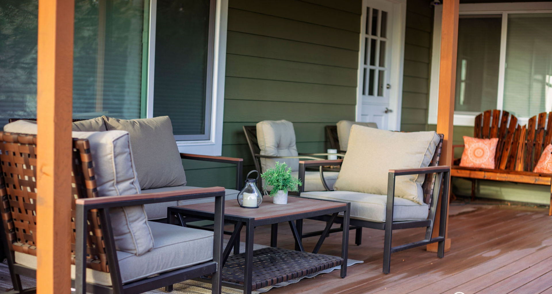 A porch with a couch , chairs , a table and a bench.