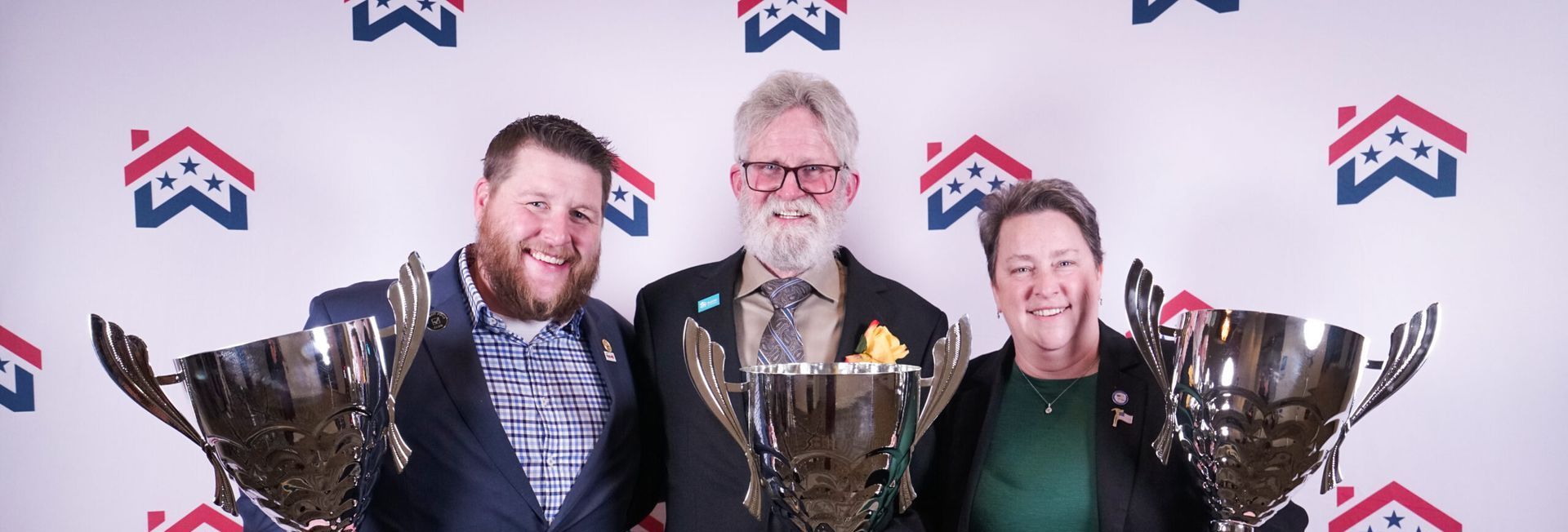 Three people are standing next to each other holding BIAW awards.