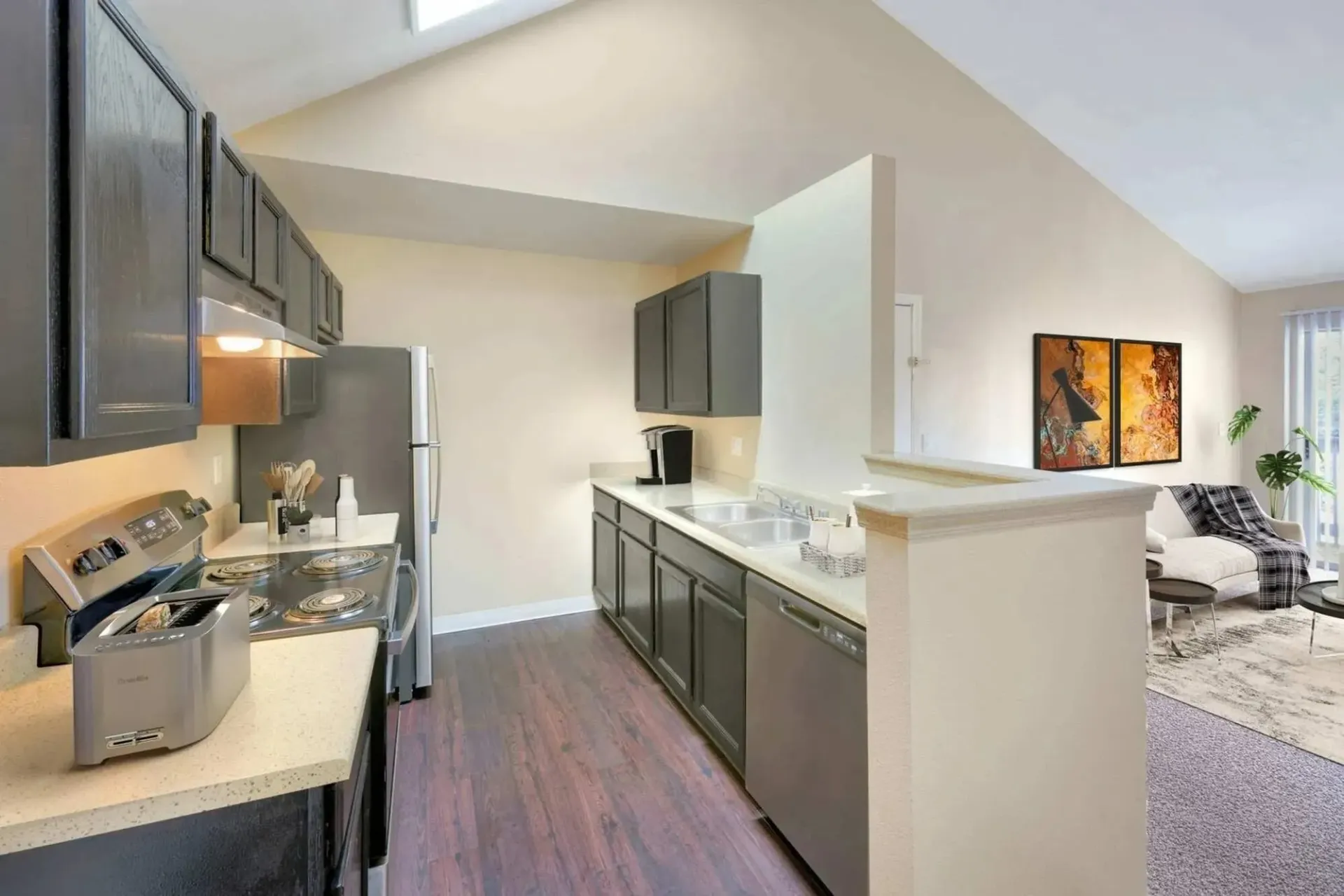 Modern kitchen with dark cabinets, stainless steel appliances, and a toaster on the counter.