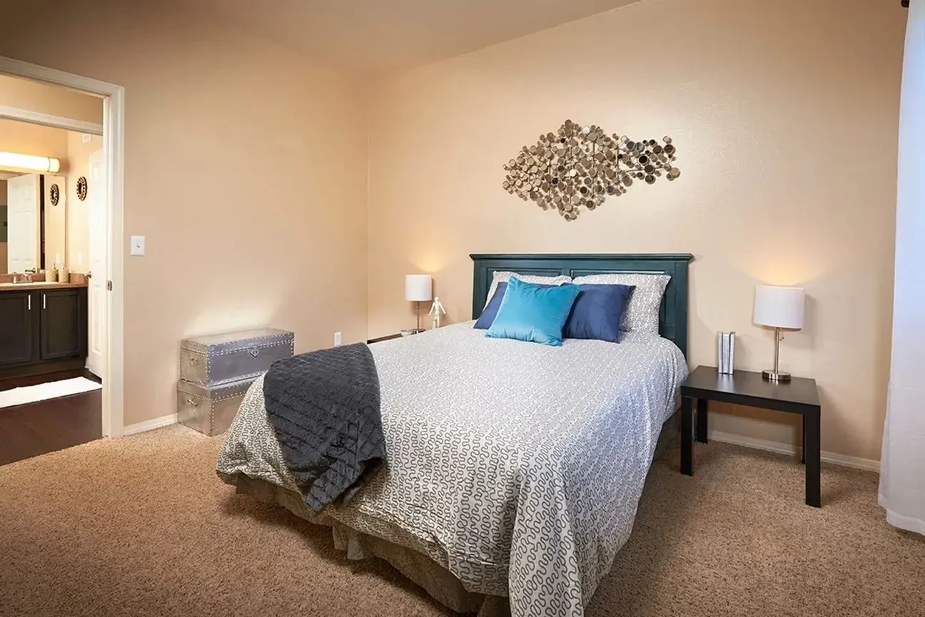 Bedroom with a queen-size bed, nightstand, and decorative wall art.