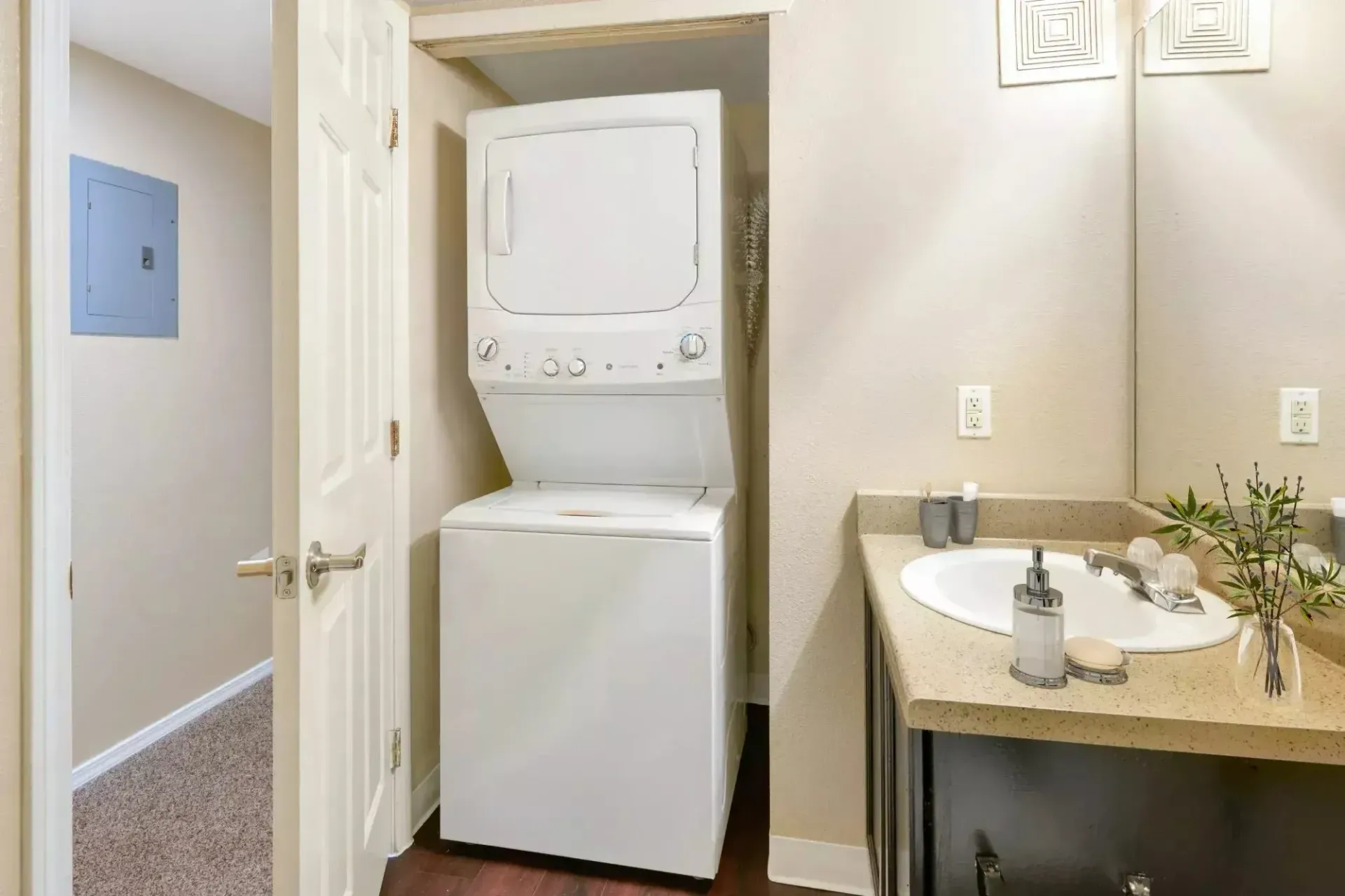 Stackable washer and dryer in a closet next to a bathroom sink.