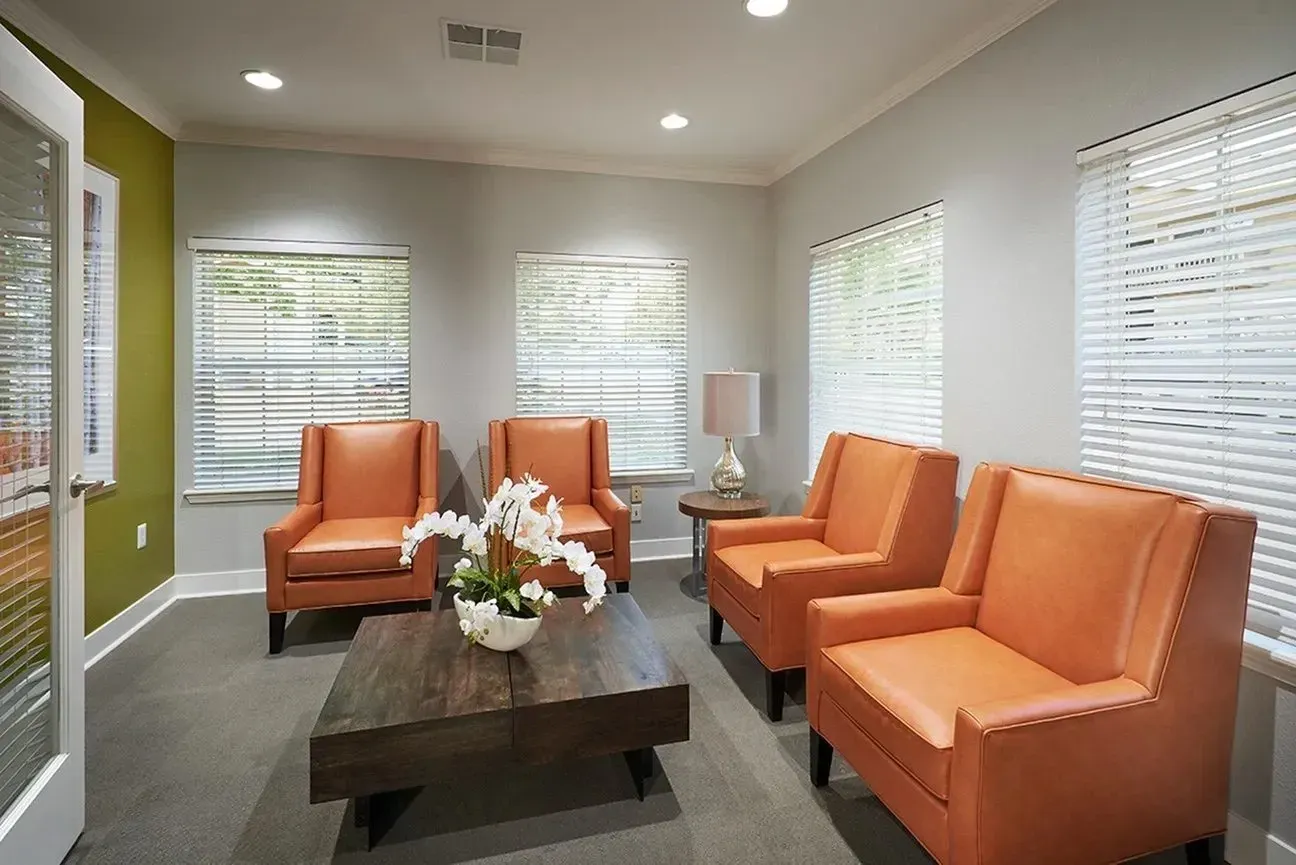 Waiting area with orange chairs and a coffee table.