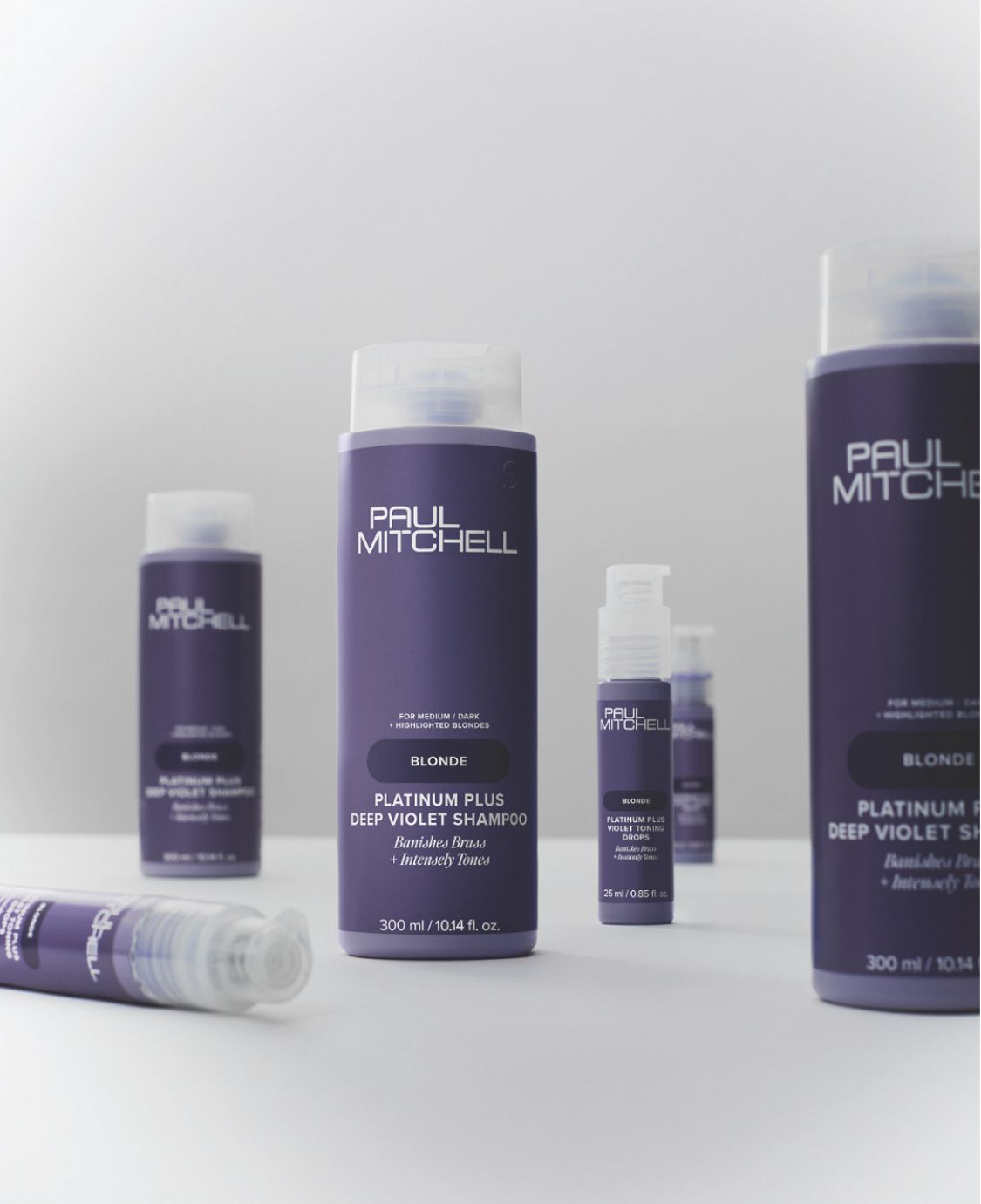Una collezione di flaconi viola di prodotti per la cura dei capelli Paul Mitchell Platinum Plus disposti su uno sfondo bianco.