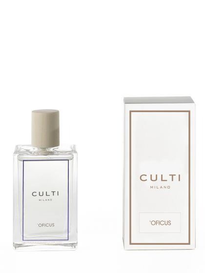 Un flacone di profumo in vetro trasparente con tappo beige accanto alla sua scatola bianca, entrambi con le etichette