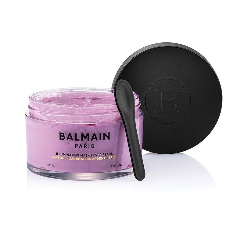 Una maschera illuminante per capelli Balmain Paris in un vasetto color lavanda con coperchio nero e spatola applicatrice abbinata.